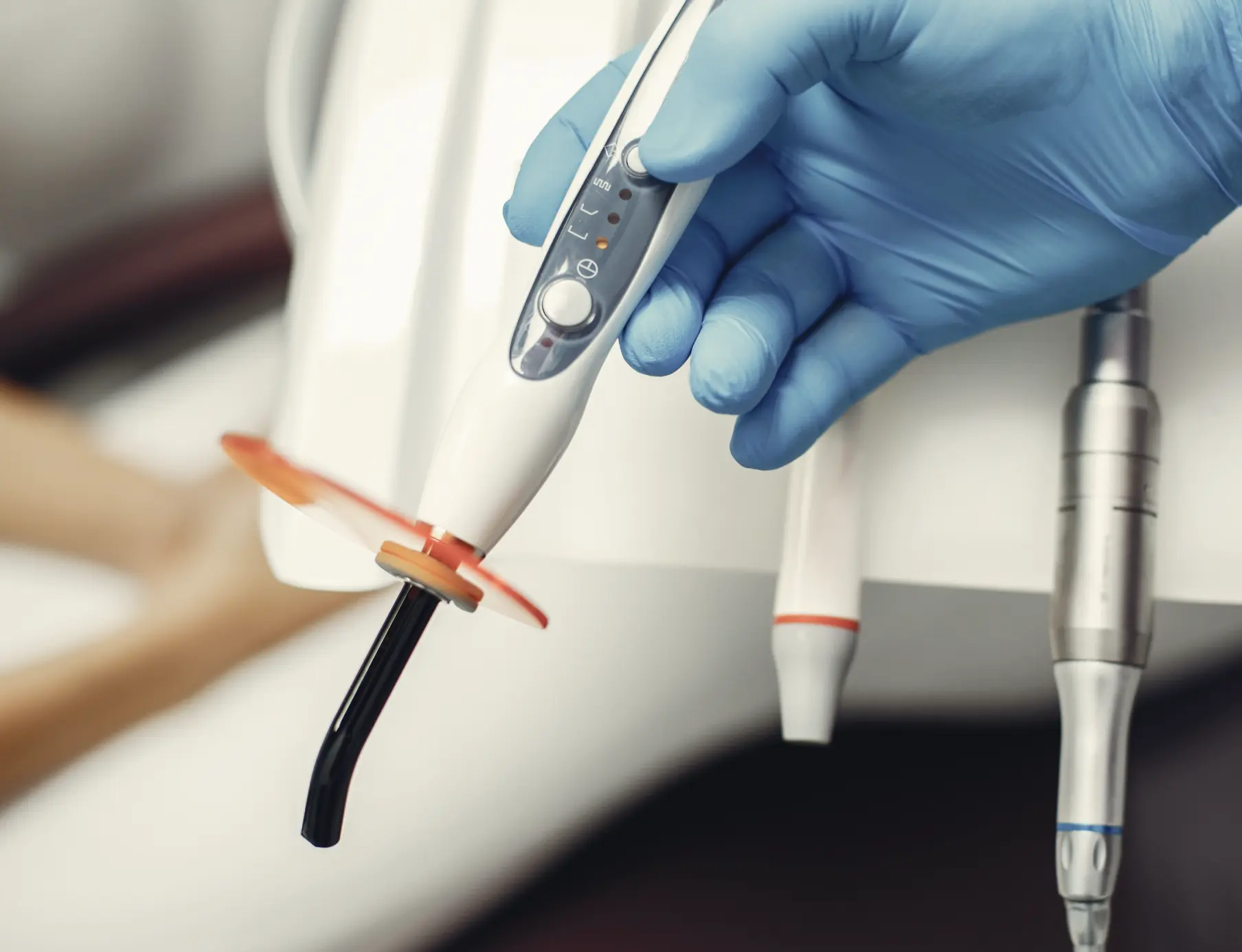 Dental light-curing instrument in gloved hand