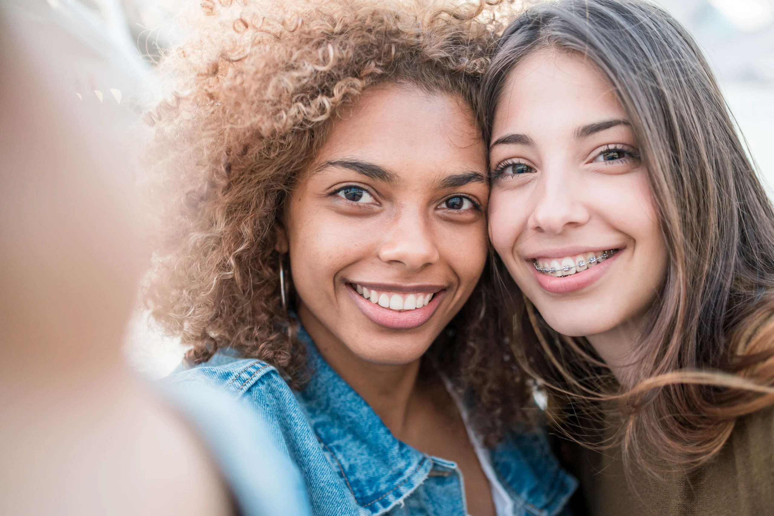 Two smiling teens, one with braces